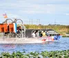 A group of people are enjoying a ride on an airboat gliding through a waterway likely in a swamp or wetlands area