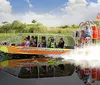 A group of people are enjoying a ride on an airboat gliding through a waterway likely in a swamp or wetlands area