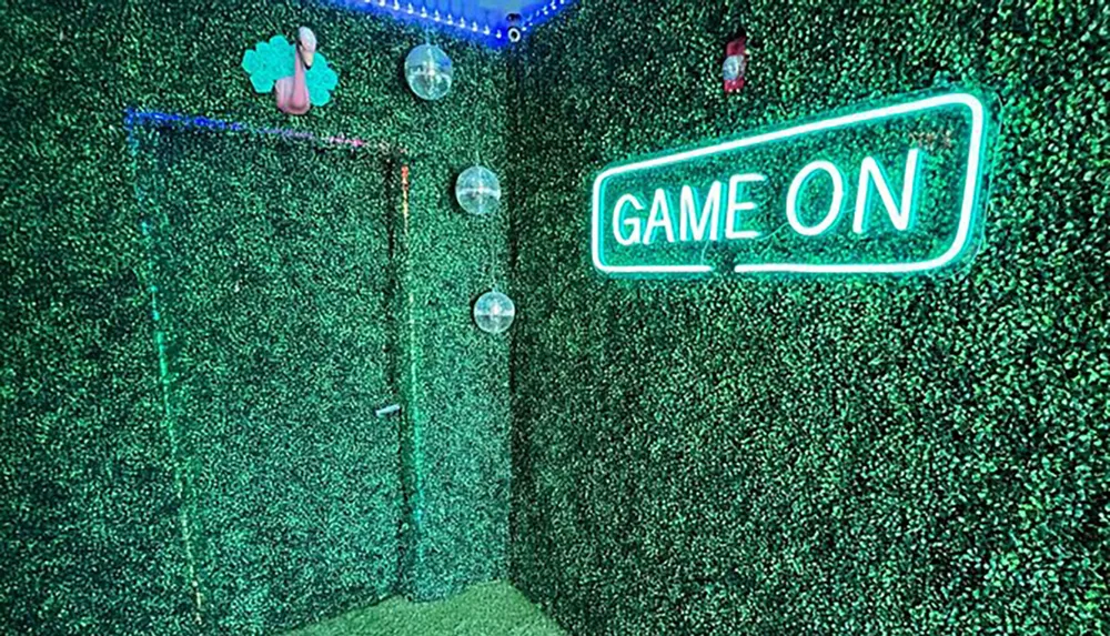 This image shows a vibrant neon sign stating GAME ON mounted on a wall covered in greenery giving off a lively playful vibe