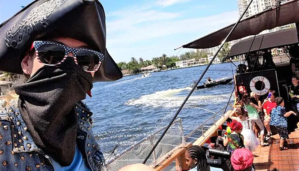 A person dressed as a pirate takes a selfie aboard a ship with passengers in the background
