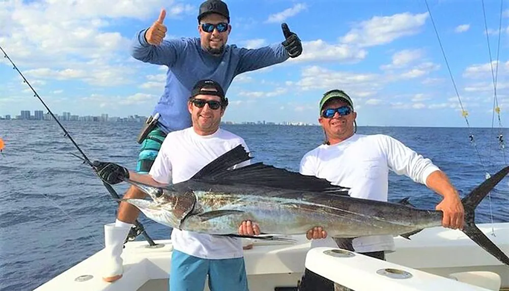 Three men on a boat proudly display a large fish theyve caught with one giving a thumbs-up and smiles all around against a backdrop of the ocean and distant city skyline