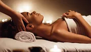 The image depicts a serene scene of a person receiving a head massage in a candlelit setting, suggesting a relaxed and soothing spa experience.