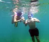 Two people are snorkeling underwater in clear blue water