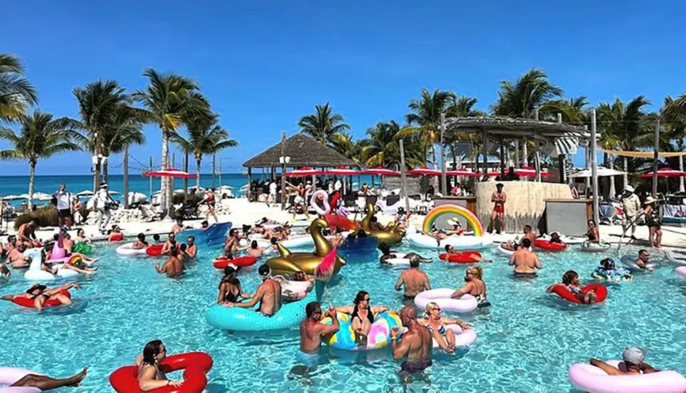 The image depicts a lively pool party with numerous people lounging on colorful floaties under a clear blue sky surrounded by palm trees
