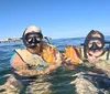 A person wearing a snorkeling mask and a life vest is flashing the peace sign with both hands while floating in the ocean
