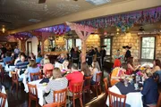 Guests are dining in a festively decorated room while being entertained by a group of mariachi musicians.