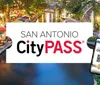 The image shows an advertisement for the San Antonio CityPASS with a picturesque view of a riverwalk area lined with colorful umbrellas and a smartphone displaying the pass