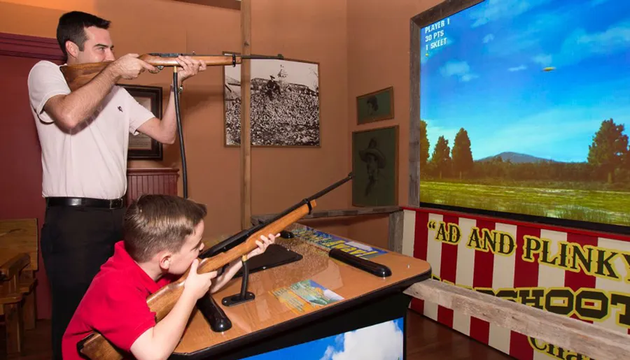 An adult and a child are playing a light gun shooter game at an arcade-style setup.