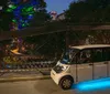 A person is standing confidently with arms crossed next to an electric shuttle vehicle on a city street at night