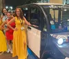 A person is standing confidently with arms crossed next to an electric shuttle vehicle on a city street at night