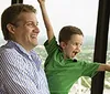 A man and a child joyfully look out at a scenic view with a quote saying Really fun experience and a great view attributed to Aaron