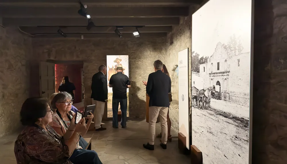 Visitors are engaged in viewing historical displays and photographs at an indoor exhibition or museum