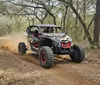 A rugged off-road vehicle is driving through a forest trail kicking up dust as it speeds along