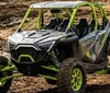 A rugged off-road vehicle is driving through a forest trail kicking up dust as it speeds along