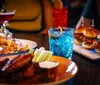 A group of joyful friends is toasting with drinks at a restaurant table filled with food