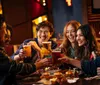 A group of joyful friends is toasting with drinks at a restaurant table filled with food