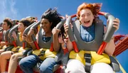 A group of excited people are enjoying a thrilling ride on a roller coaster under a clear blue sky.