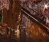 A family is admiring an underground pool in a beautifully lit cave with intricate rock formations surrounding them