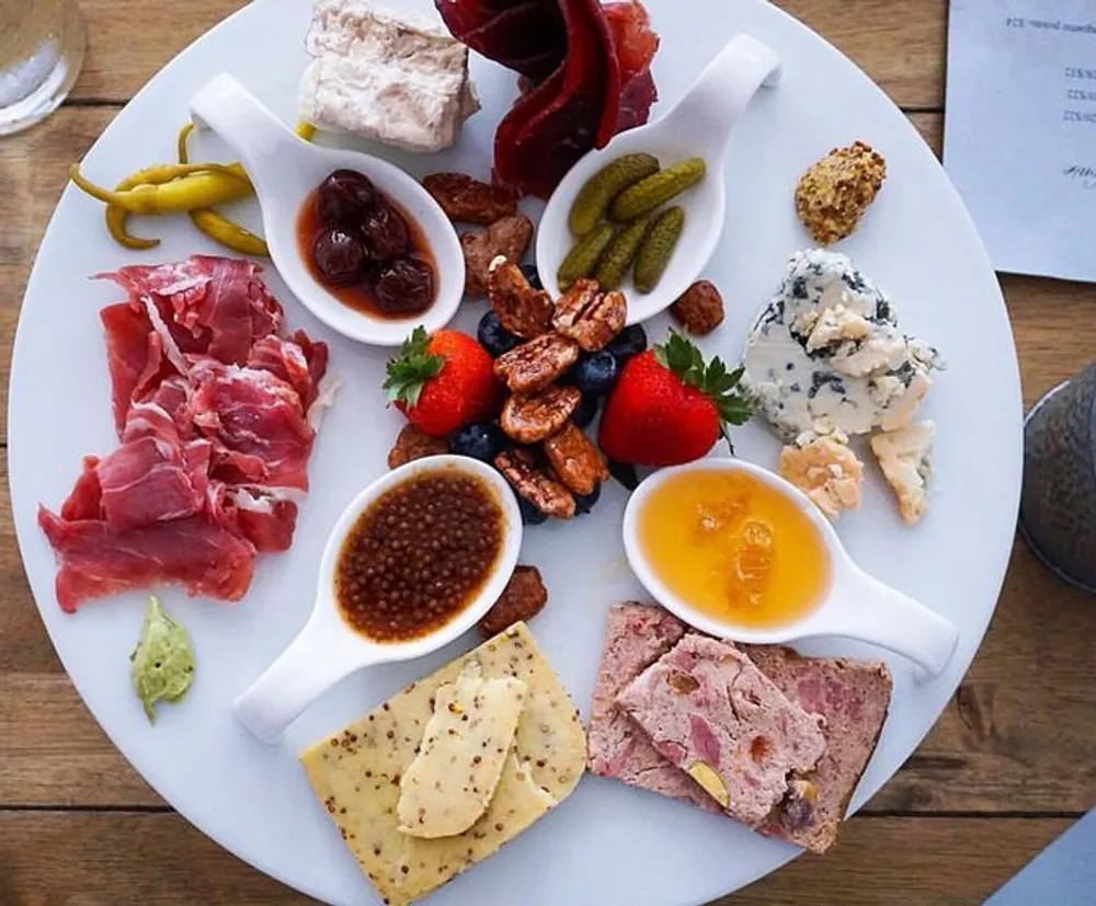 The image shows an appetizing charcuterie board with an array of meats cheeses fruits nuts and condiments arranged for an elegant snacking experience