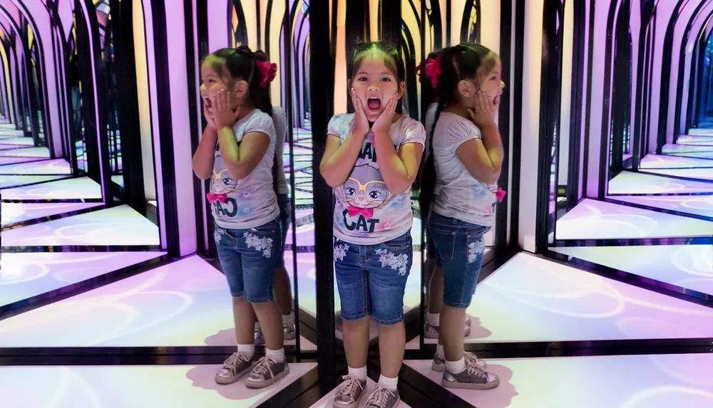 A young girl is shouting excitedly while standing in a mirrored corridor creating an illusion of multiple reflections
