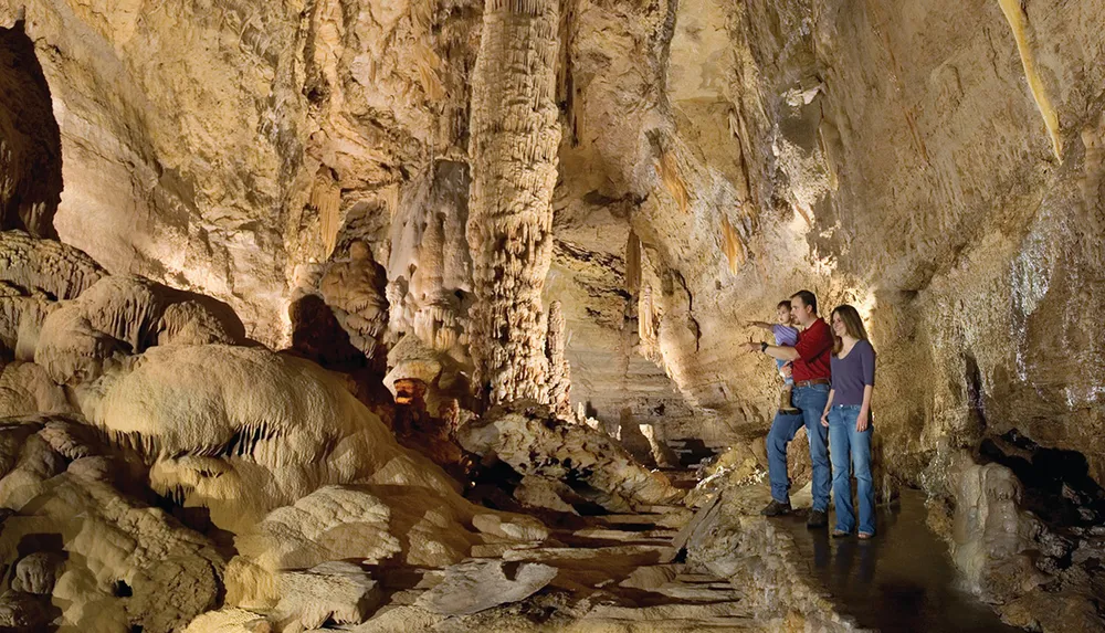 A group of people is admiring the stunning formations inside a spacious well-lit cave