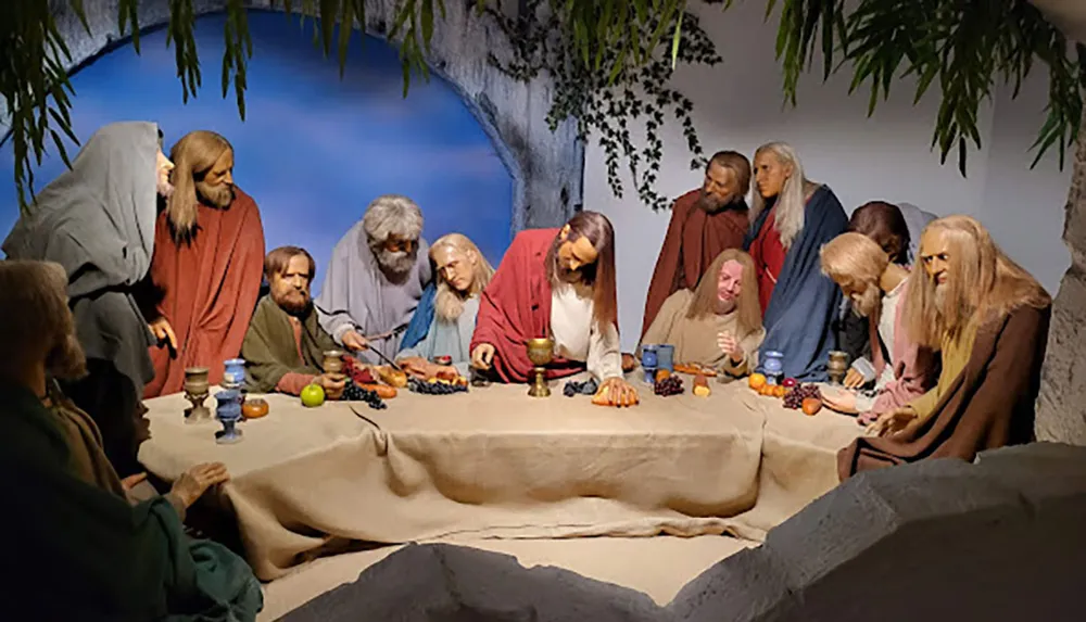 The image shows a life-sized diorama or representation of the Last Supper with figures positioned around a table in a setting designed to resemble the famous scene