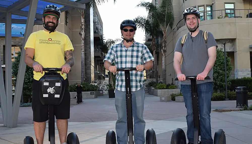 Three men wearing helmets are standing with their Segways smiling at the camera