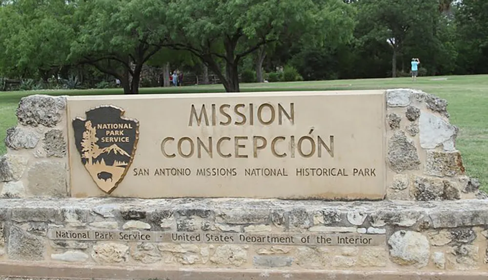 The image shows a textured stone sign for Mission Concepcin at the San Antonio Missions National Historical Park affiliated with the National Park Service and the United States Department of the Interior