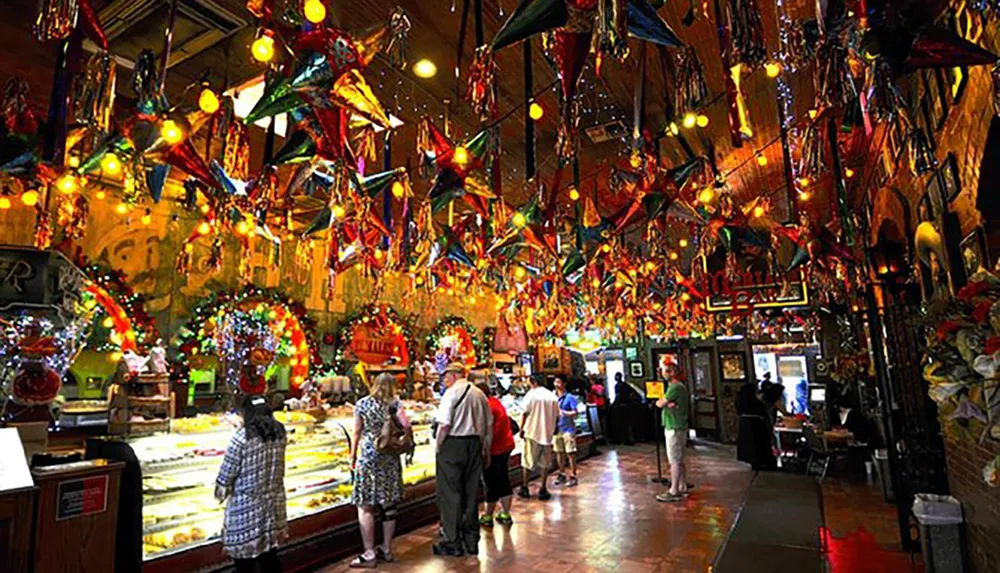 This image depicts a lively and colorful indoor market or restaurant adorned with numerous festive decorations and patrons browsing or queuing for service