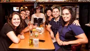 A group of people are posing happily for a photo at a table inside a bar or restaurant.