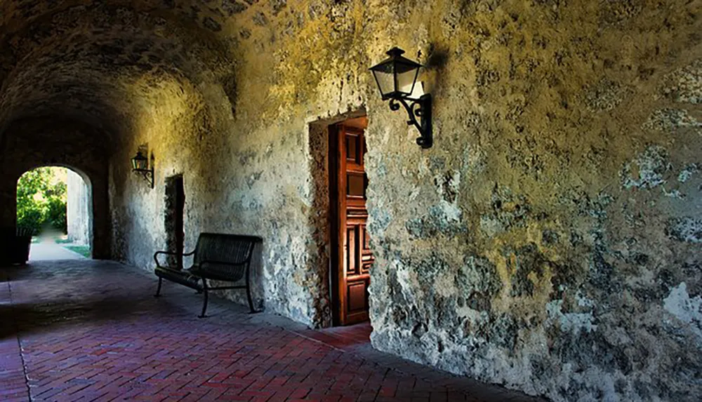 The image shows a serene historic corridor with an arched entrance a weathered wall a lantern a wooden door and a bench highlighting the textures and atmosphere of a bygone era
