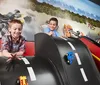 Two children are joyfully playing with toy cars on a specially designed race track that emulates a real racing scenario with a dynamic racing-themed mural in the background