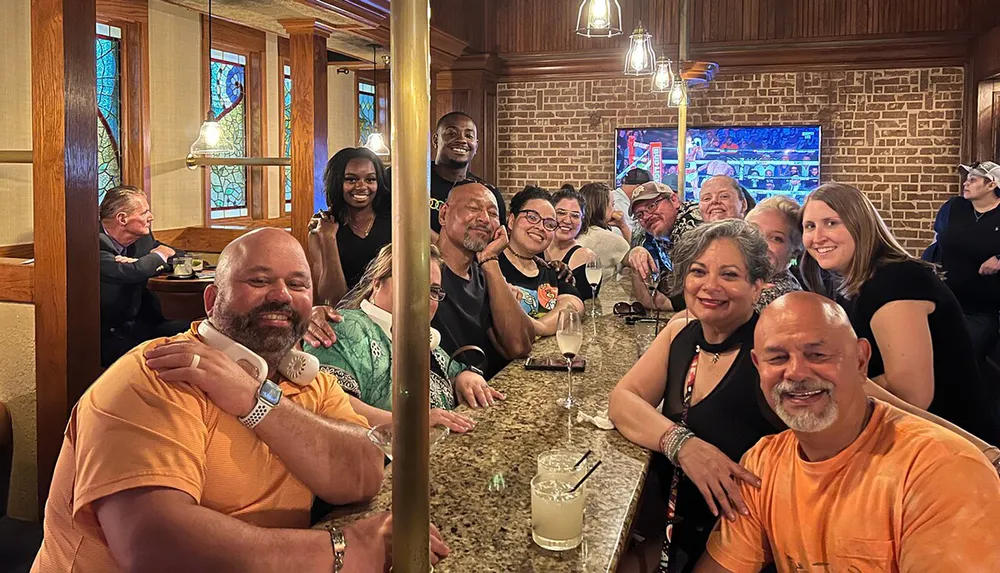 A group of smiling people are enjoying each others company at a bar with drinks creating a lively and convivial atmosphere