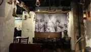 The image shows a rustic restaurant interior with a large wall mural depicting historical figures, complemented by antique décor and hanging old-fashioned lanterns, creating a vintage atmosphere.