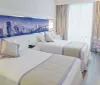The image shows a modernly designed hotel room with a large bed a wall art featuring a bridge sheer curtains and a simple desk with a chair