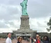 A group of five individuals is posing for a photo with the Statue of Liberty towering in the background
