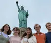 A group of five individuals is posing for a photo with the Statue of Liberty towering in the background