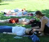 Three people are practicing yoga in a park with skyscrapers in the background