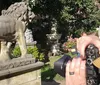 A photographer is capturing a scene featuring a lion statue with various other classical statues and a garden in the background