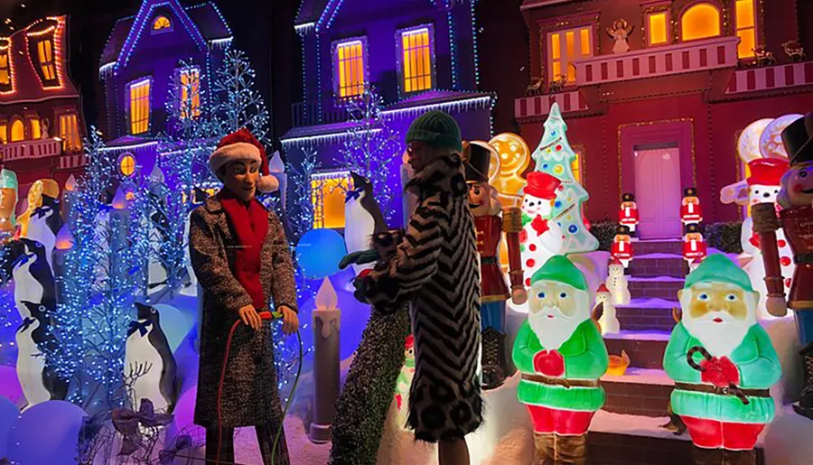 Visitors are engaging with a colorful and brightly lit Christmas-themed display featuring oversized decorations and festive figurines.