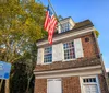 This image is a collage showcasing various iconic American scenes including the United States Capitol building historical colonial architecture an Amish market a bustling cobblestone street and a sculpture of Benjamin Franklin reflecting diverse aspects of American culture and history