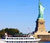 A ferry full of passengers sails near the Statue of Liberty under a clear blue sky
