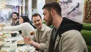 A group of people are enjoying a meal together at a restaurant with Chinese-style decor.