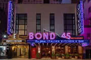The image shows the brightly lit neon sign of Bond 45, a New York Italian kitchen and bar, with the Hotel Edison sign displayed above it.
