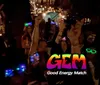 A group of people appear to be enjoying a social event at night wearing glowing headbands and accessories with a logo and text GEM - Good Energy Match superimposed onto the image