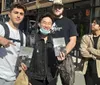 Four individuals are standing outdoors with three of them holding copies of a book titled CASH and one person pointing at a book while two of them smile at the camera and two look on