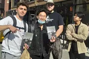 Four individuals are standing outdoors, with three of them holding copies of a book titled 