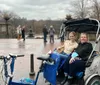 A group of smiling people are enjoying a pedicab ride on a city street during a chilly day