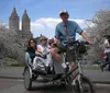 A group of smiling people are enjoying a pedicab ride on a city street during a chilly day