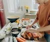 A person is preparing sushi with various ingredients spread out on a kitchen counter